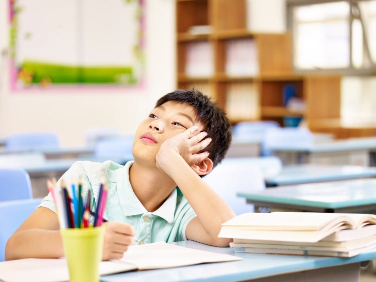 Child in school, staring off and daydreaming when he should be focusing on school. Read on to learn how at home neurofeedback can help improve focus, attention and mental acuity.
